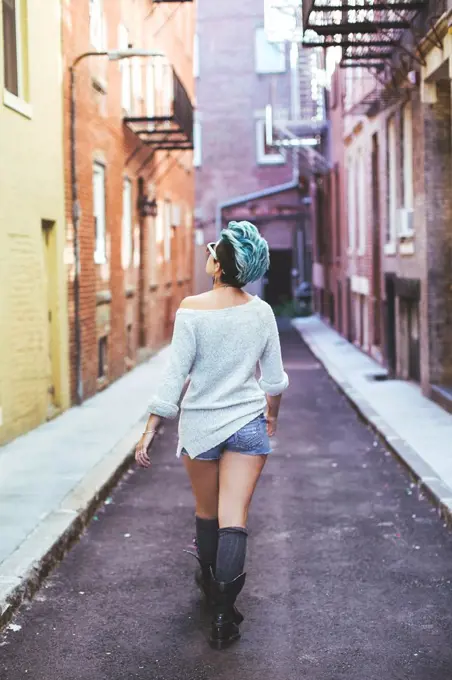 Caucasian woman walking in urban alleyway