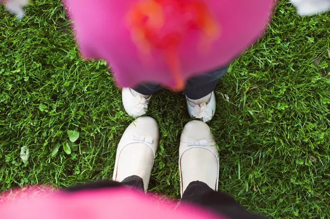 High angle view of feet of mother and daughter in grass