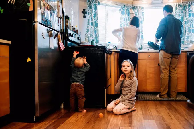 Children playing as parents cook in kitchen