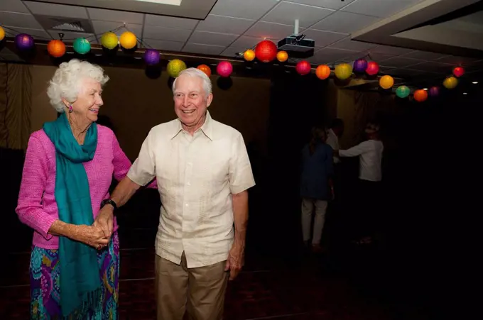 Older Caucasian couple dancing at party in retirement home