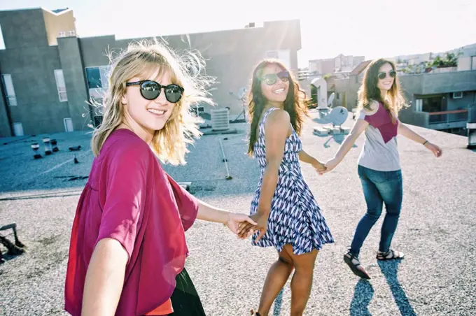 Women holding hands on urban rooftop