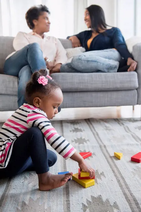 black baby girl playing on carpet with blocks