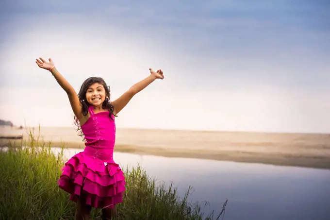 Hispanic girl cheering by still water