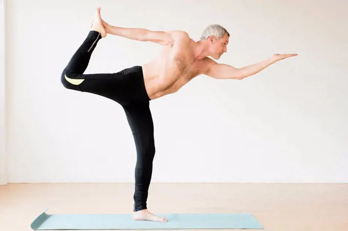 Older Caucasian man doing yoga on exercise mat