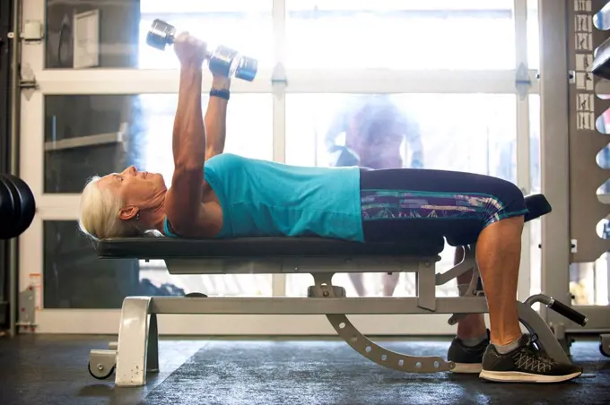 Older woman lifting dumbbells in gymnasium