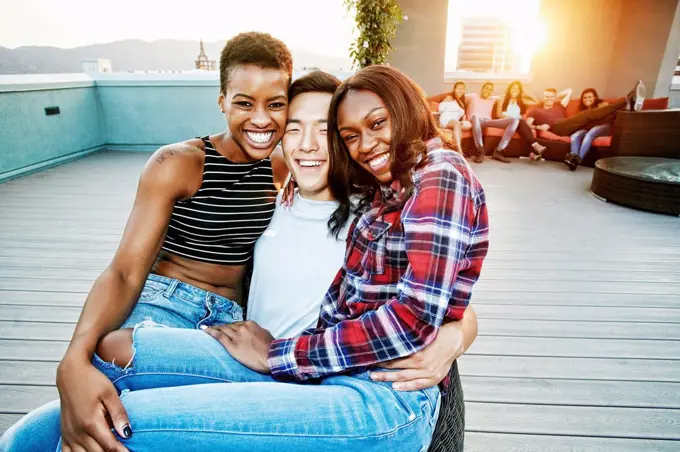 Portrait of smiling women on lap of man on rooftop