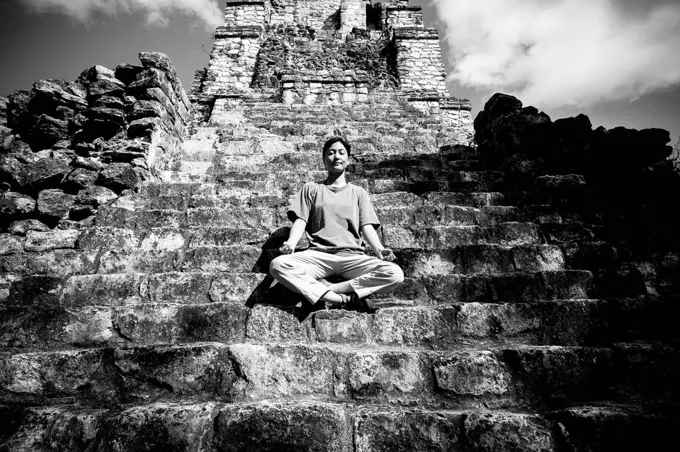 Japanese woman meditating on staircase to temple