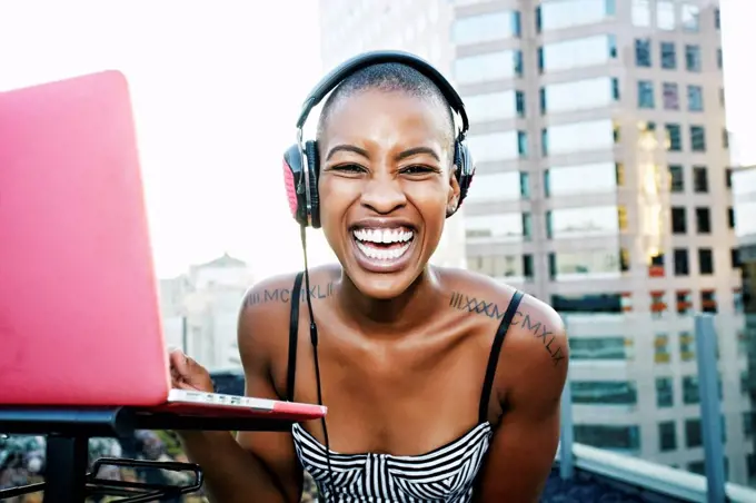 Portrait of Black DJ laughing on urban rooftop