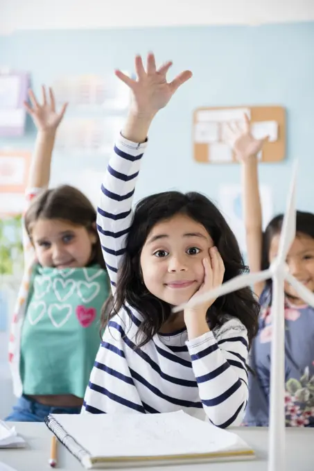 Girls learning about windmills raising hands in classroom