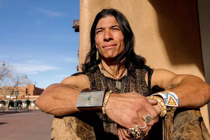 Native American man sitting against post