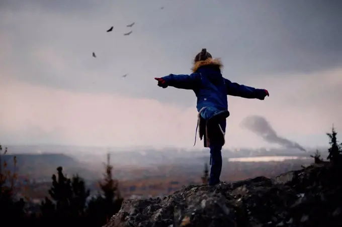 Caucasian girl balancing on rocks imitating flying birds