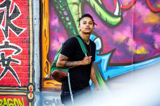 Portrait of androgynous Mixed Race woman near graffiti wall