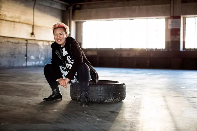 Portrait of smiling androgynous Asian woman sitting on wheel