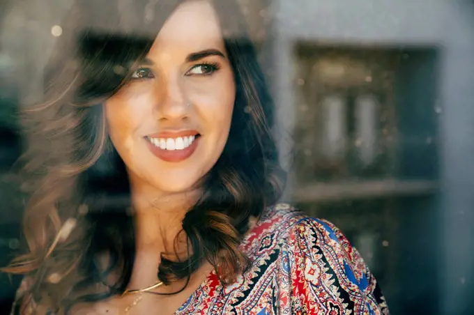 Portrait of smiling Mixed Race woman behind window