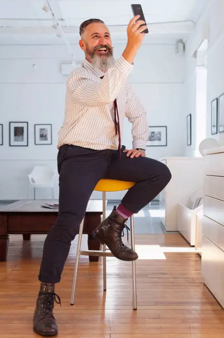 Smiling Caucasian businessman posing for cell phone selfie