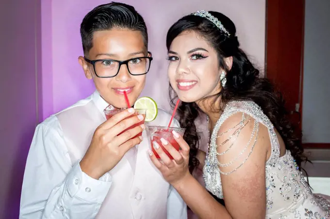 Hispanic boy and girl drinking beverages with straws