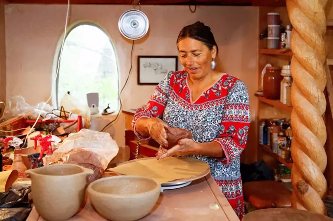 Mixed race woman shaping clay in art studio