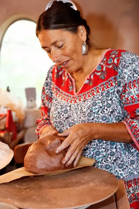 Mixed race woman shaping clay in art studio