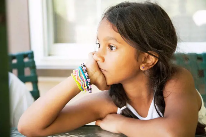 Pensive Hispanic girl with head in hands