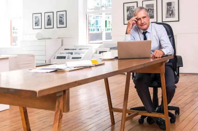 Portrait of frustrated Caucasian businessman using laptop