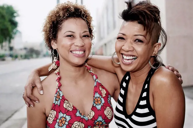 Smiling women hugging on urban street