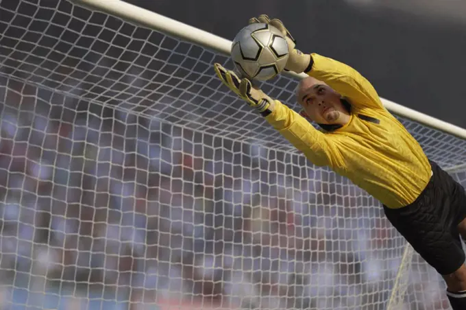 Male goalie catching ball in midair