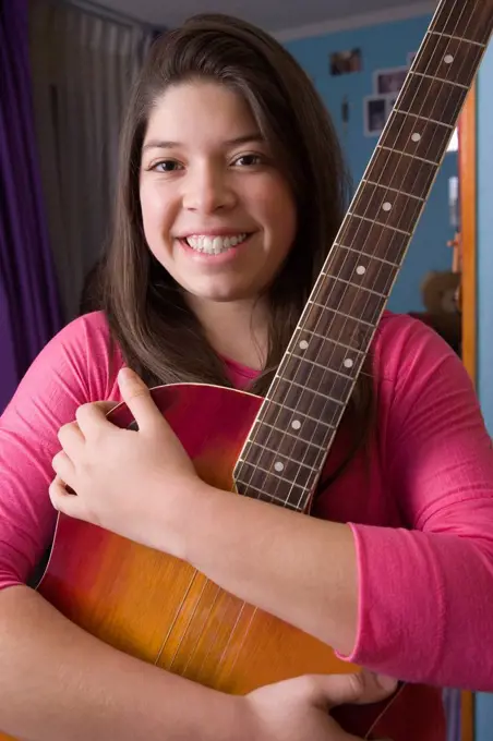 Hispanic girl hugging guitar