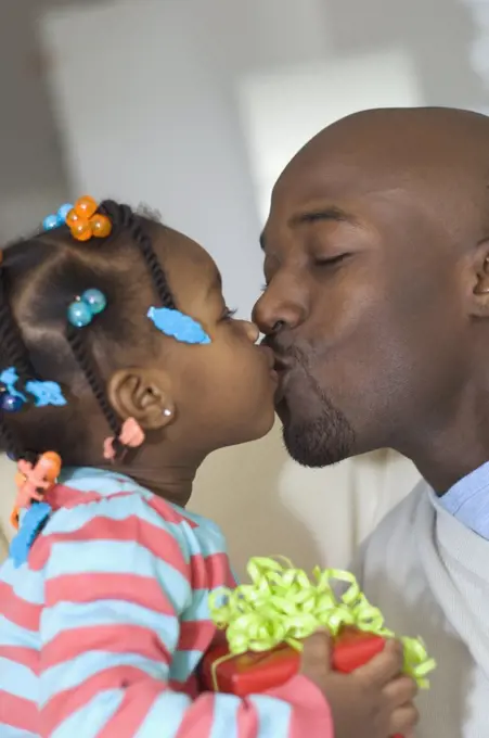 African girl giving gift to father