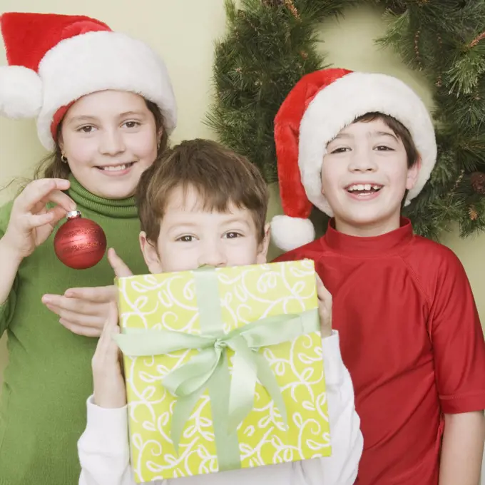 Hispanic siblings in Santa Claus hats with gift