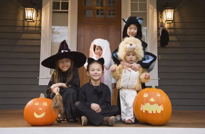 Children in Halloween costumes with pumpkins