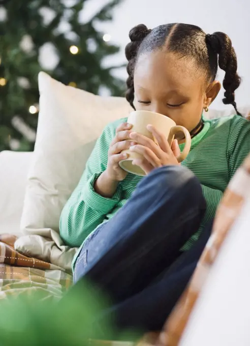 African American girl drinking hot chocolate on sofa