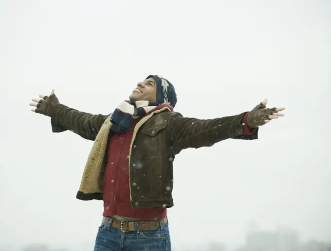 African American man standing in snow with arms outstretched