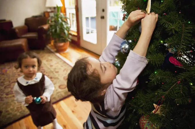 Mixed race girl decorating Christmas tree