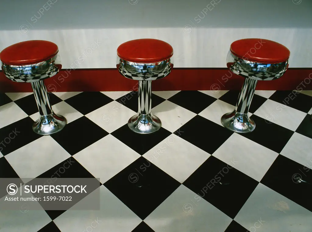 This is an art deco style restaurant. It has a black and white checkerboard tile floor with red vinyl stools next to the counter. It is a typical 50's style diner.