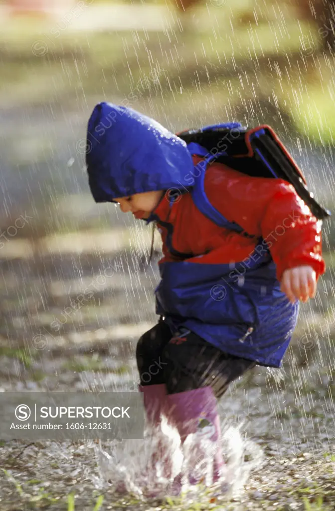 Young boy jumping in puddle