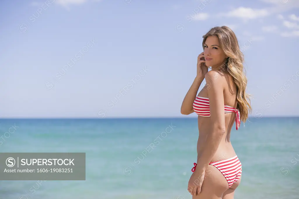 Portrait of a sexy blonde woman in bikini at the beach seducing camera -  SuperStock