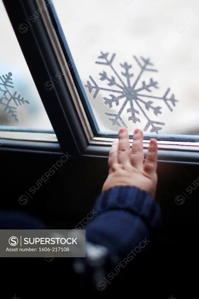 A boy's hand in front of a window with Christmas decorations