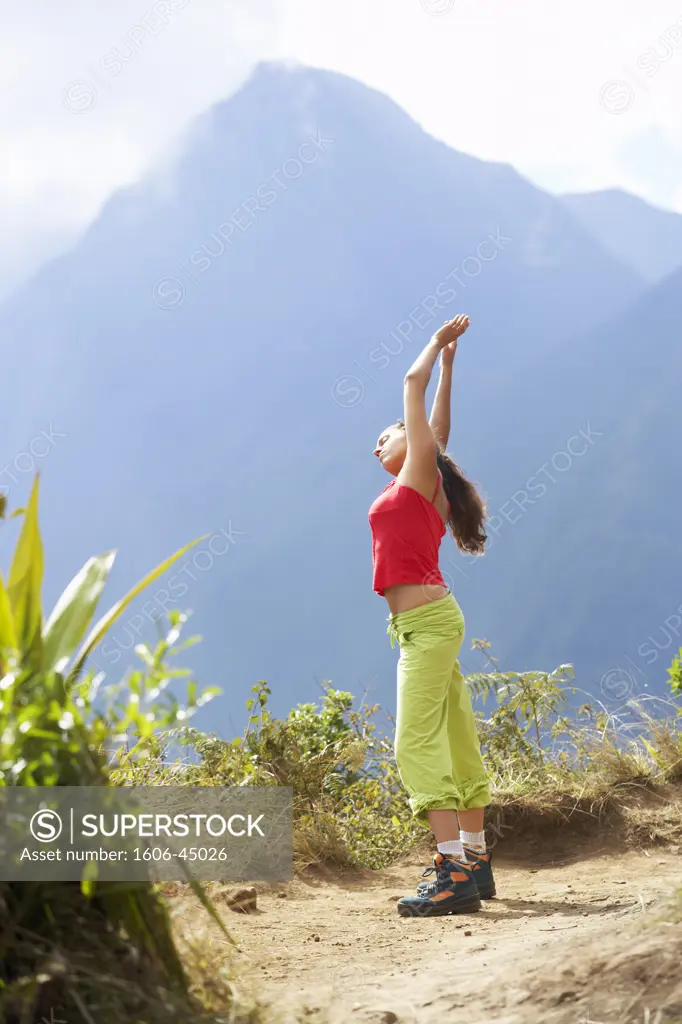 Reunion island, young woman making stretching exercices at the top of a mountain