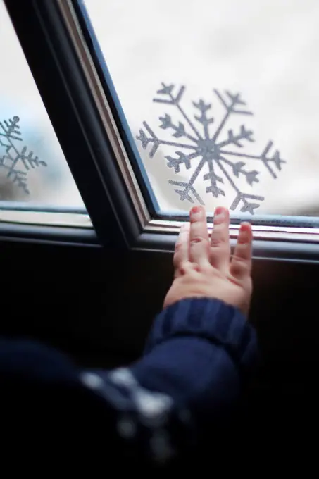 A boy's hand in front of a window with Christmas decorations