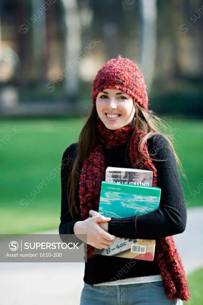 Portrait of a young woman carrying books smiling