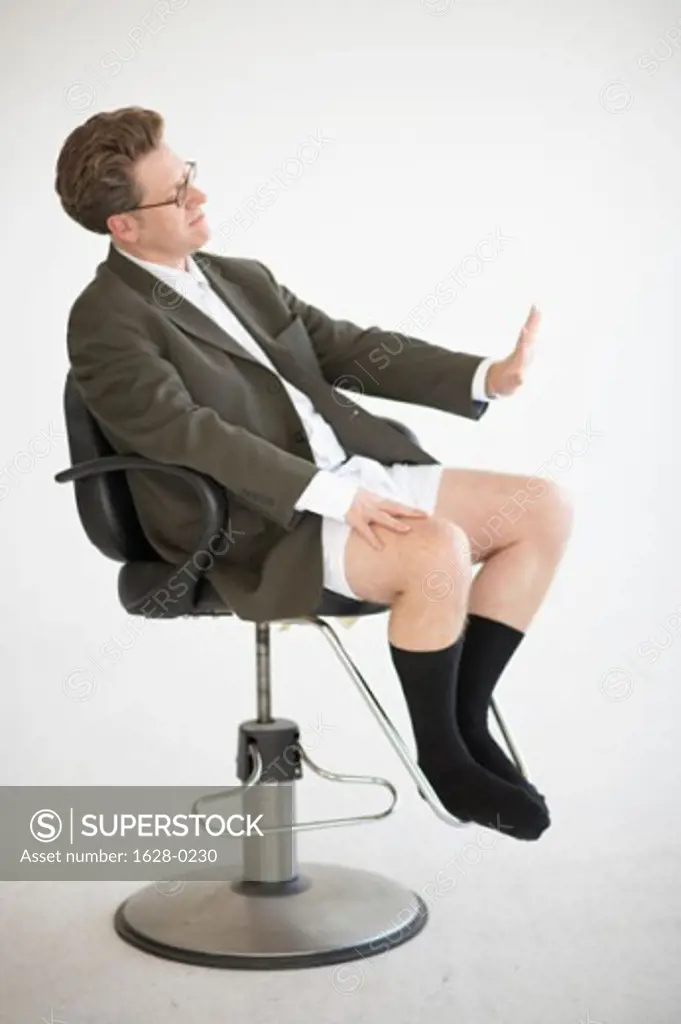 Side profile of a businessman sitting in an office chair making a stop gesture