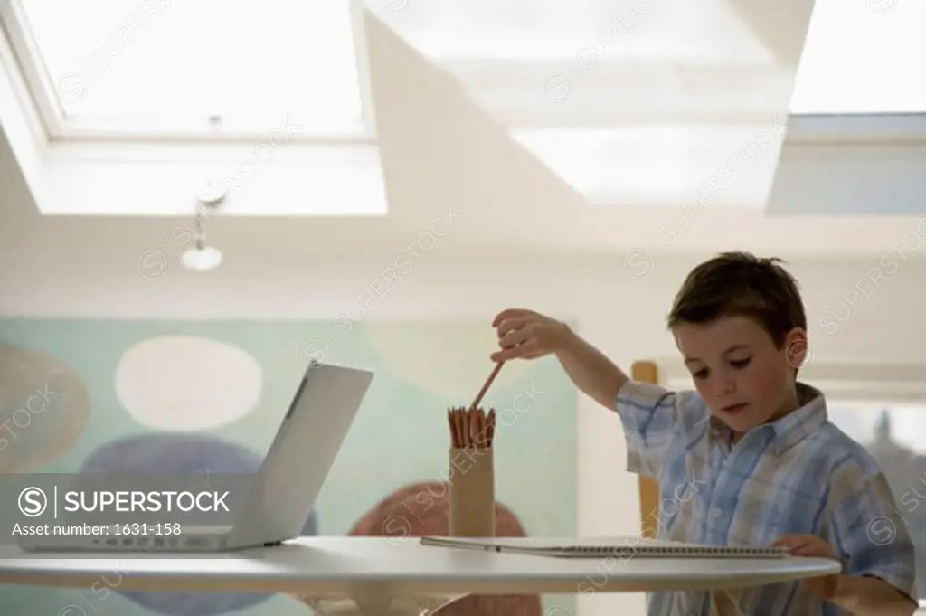 Close-up of a boy picking up a pencil