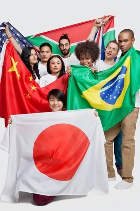 London, UK. Group of multi_ethnic friends holding various national flags against white background