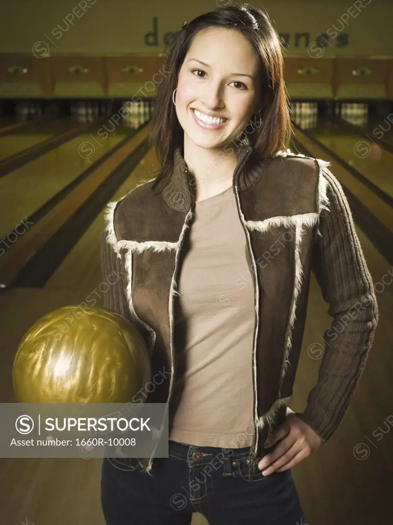 Portrait of a teenage girl holding a bowling ball and smiling