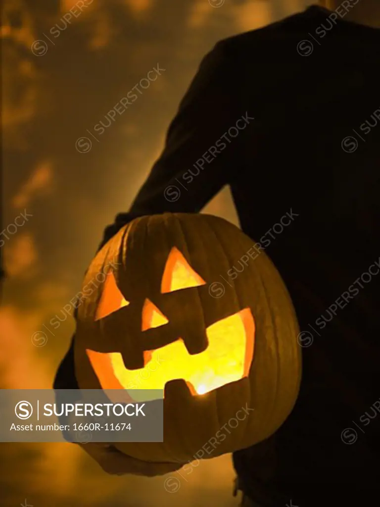 Mid section view of a person holding a Halloween lantern