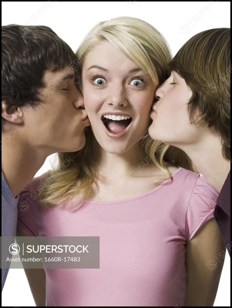 Girl being kissed on both cheeks by two boys