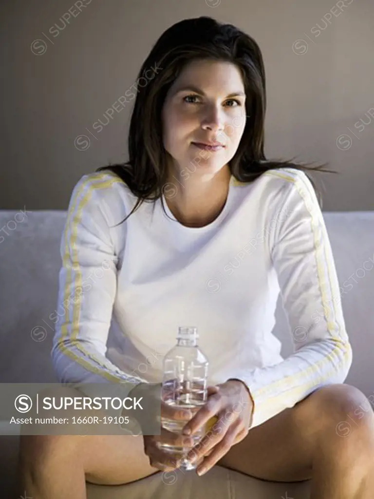 Woman sitting on sofa with bottled water