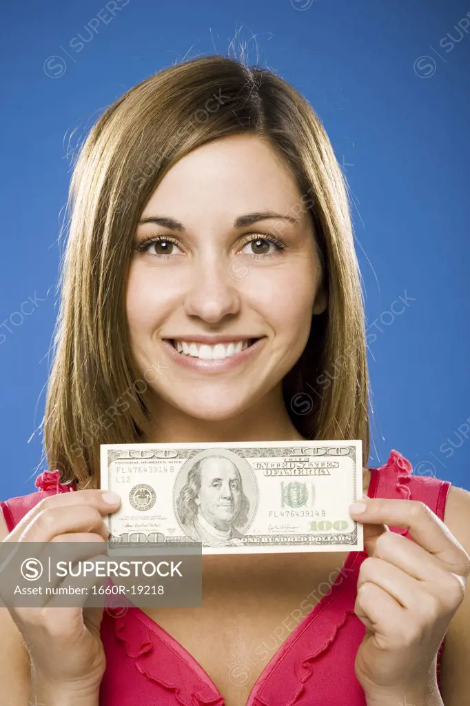 Woman holding one hundred American dollar bill smiling