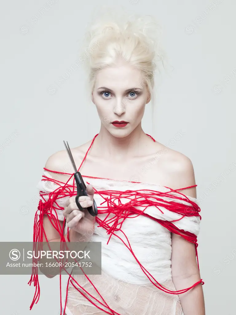 Studio portrait of young woman wrapped in red thread