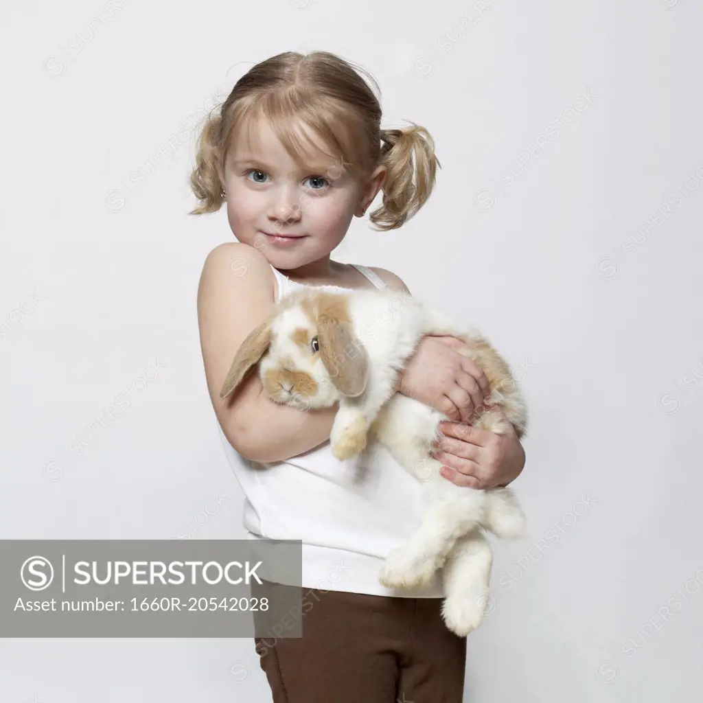 Studio shot of girl (2-3) holding rabbit